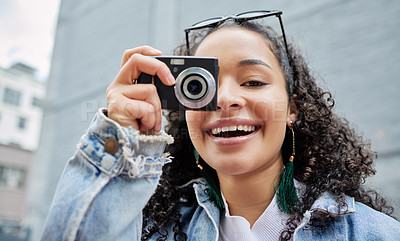 Buy stock photo Shot of a young woman holding her camera while standing outside