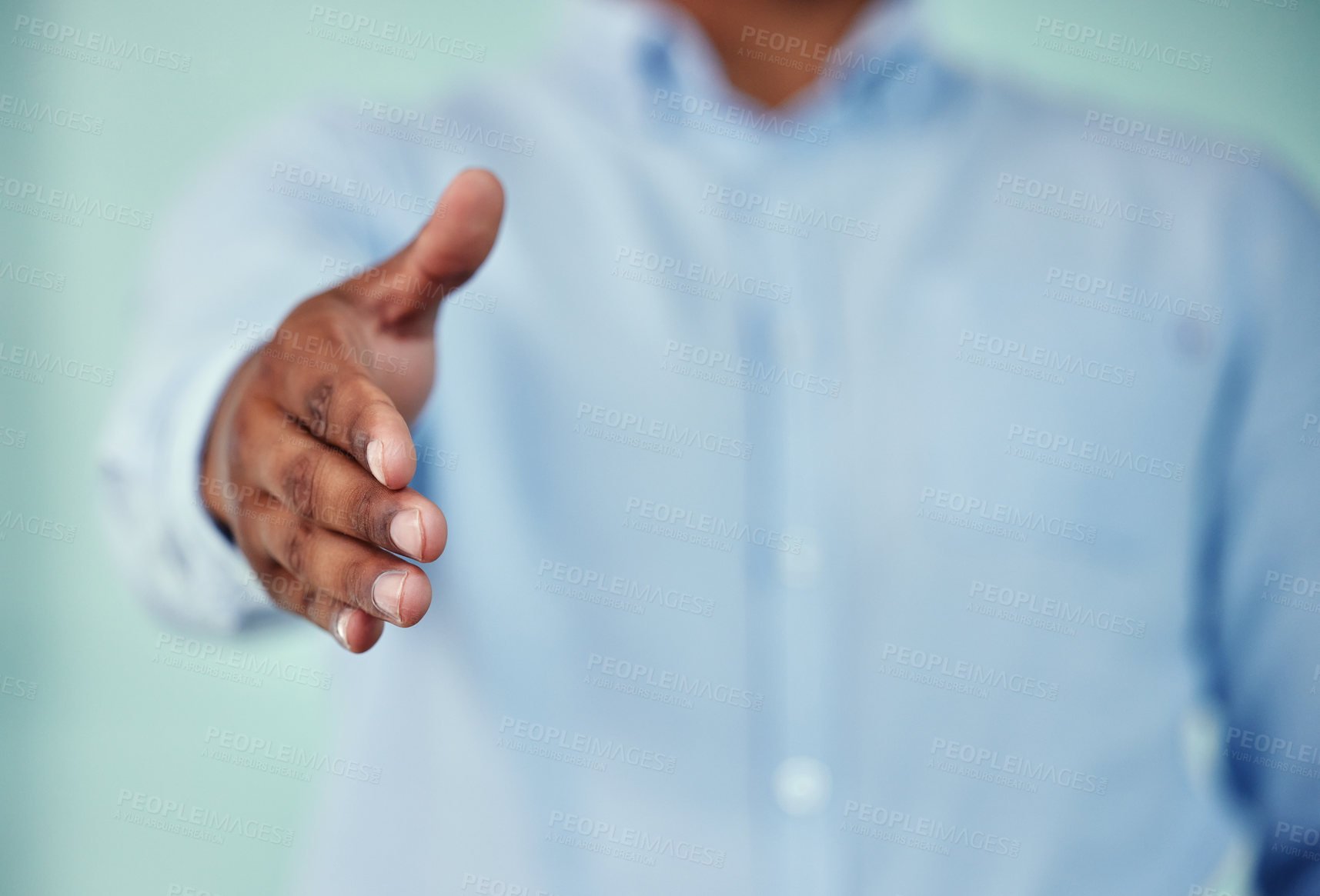 Buy stock photo Cropped shot of an unrecognizable businessman standing with his hand outstretched for a handshake against a blue background