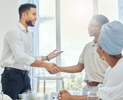 Buy stock photo Cropped shot of two handsome young businessmen shaking hands during a meeting in the boardroom