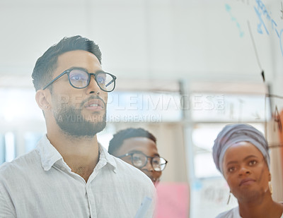 Buy stock photo Cropped shot of a group of diverse young businesspeople working on a glass wipe board in the boardroom