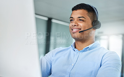 Buy stock photo Shot of a handsome young call centre agent sitting in the office and wearing a headset while using his computer