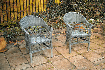 Buy stock photo Two rattan chairs in a garden patio or terrace on a sunny day in autumn. Rustic outdoor furniture in a calm and peaceful environment surrounded by nature. Cosy spot to enjoy a break with fresh air
