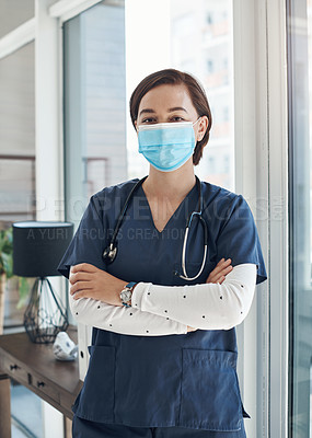 Buy stock photo Shot of a young doctor with her arms crossed while wearing a mask in an office