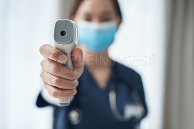 Buy stock photo Shot of a young female doctor pointing a thermometer in an office