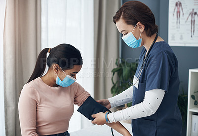 Buy stock photo Shot of a young female doctor checking a patient's blood pressure in an office