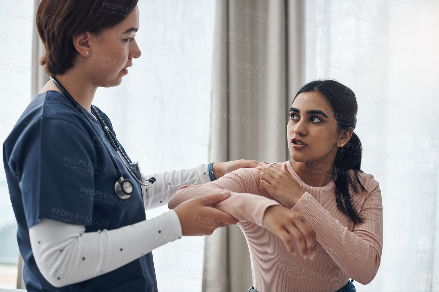 Buy stock photo Shot of a young female doctor checking a patient's arm in an office