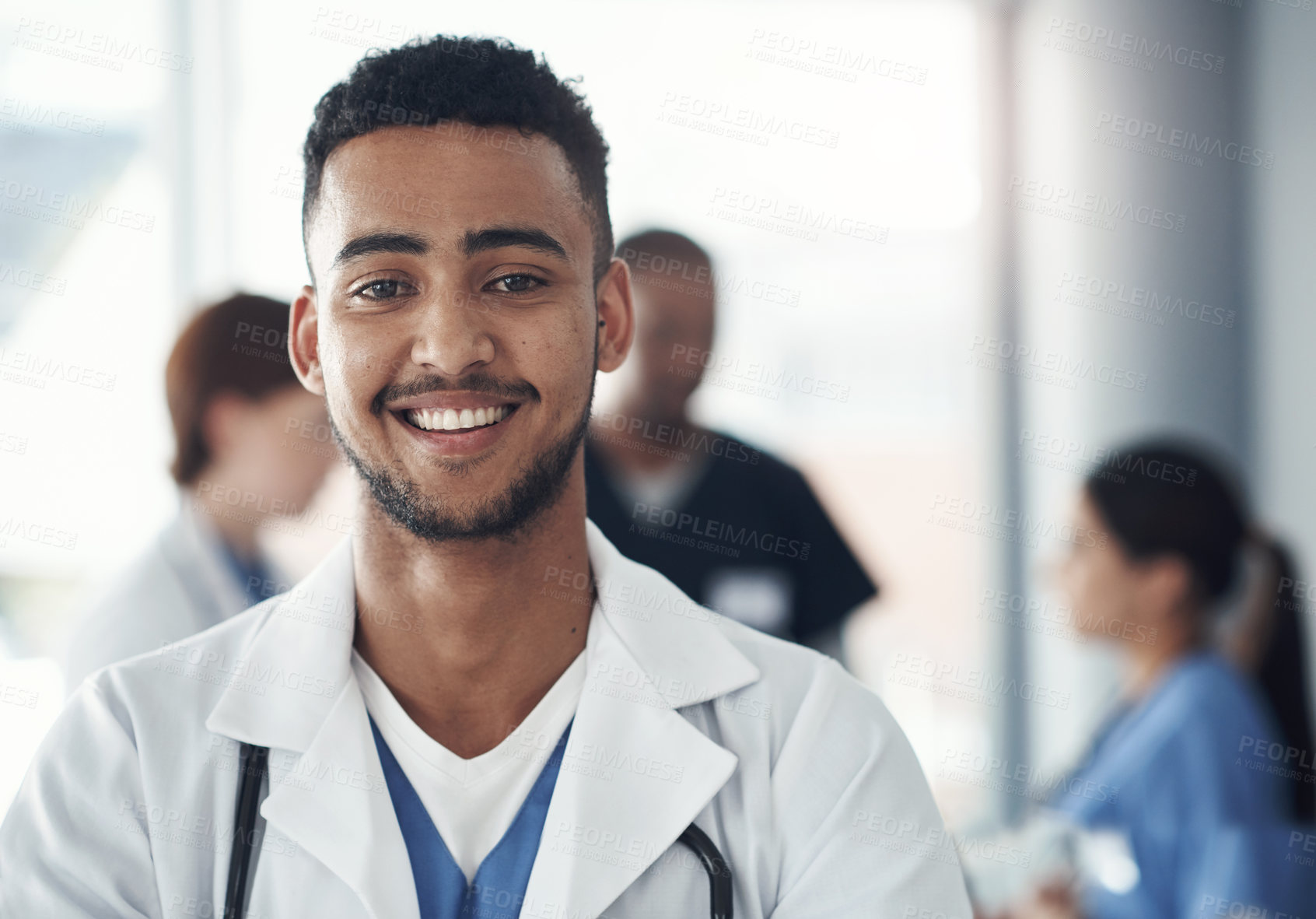 Buy stock photo Shot of a young male doctor standing in the office of a hospital