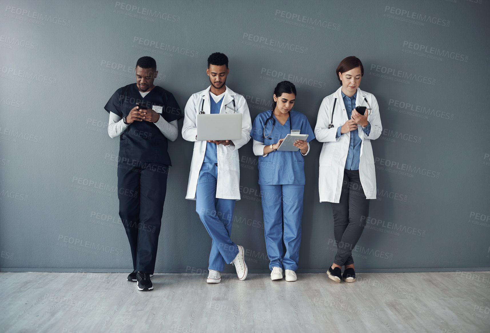 Buy stock photo Shot of a group of doctors standing against a grey background at work