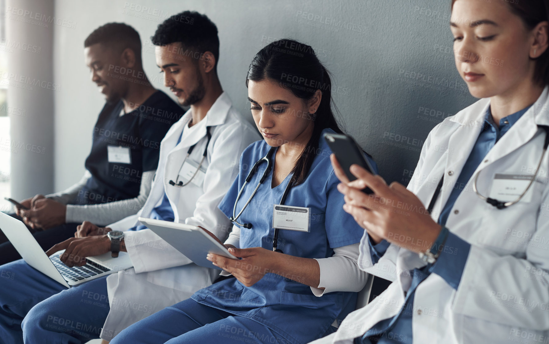 Buy stock photo Chairs, team and technology with doctors by wall for interview or public health conference and training meeting. People, medical staff and line for patient rounds or daily briefing, review and online