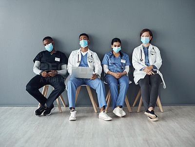 Buy stock photo Shot of a group of doctors sitting against a grey background at work