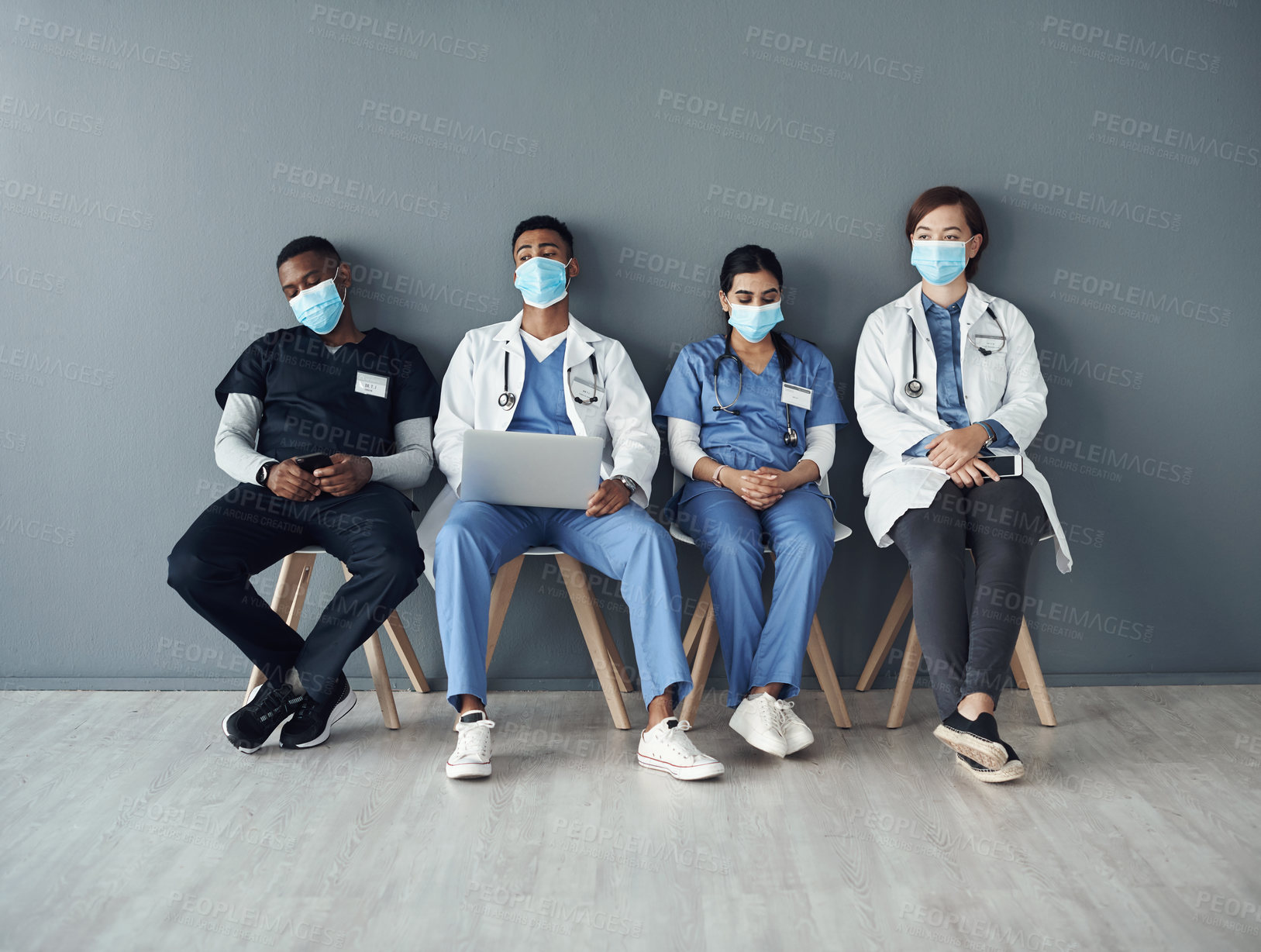 Buy stock photo Chairs, team and tired doctors by wall for interview or public health conference and training meeting. People, medical staff and line for patient rounds or daily briefing, review and medicare.