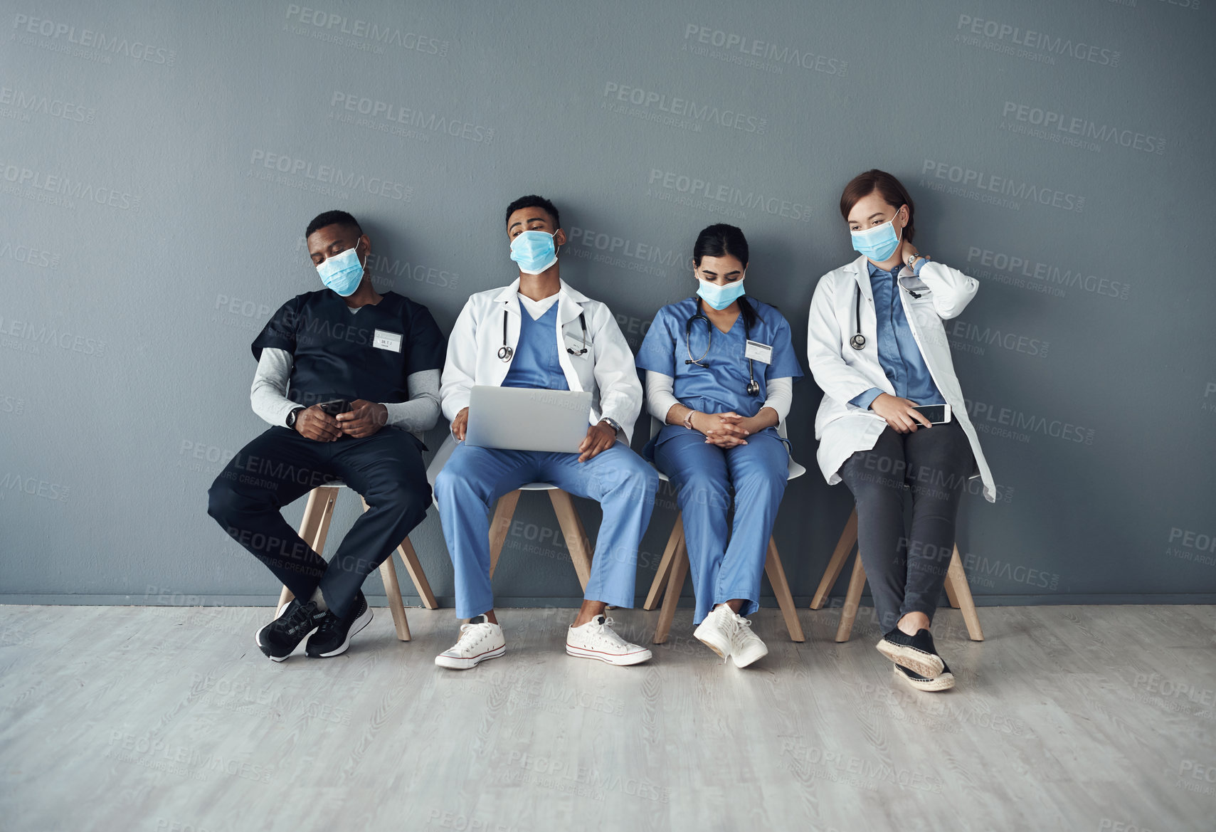 Buy stock photo Chairs, team and tired doctors by wall for interview or public health conference and training meeting. People, medical staff and line for patient rounds or daily briefing, review and exhausted.