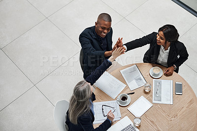 Buy stock photo High angle shot of a group of businesspeople giving each other high five during a meeting in a modern office