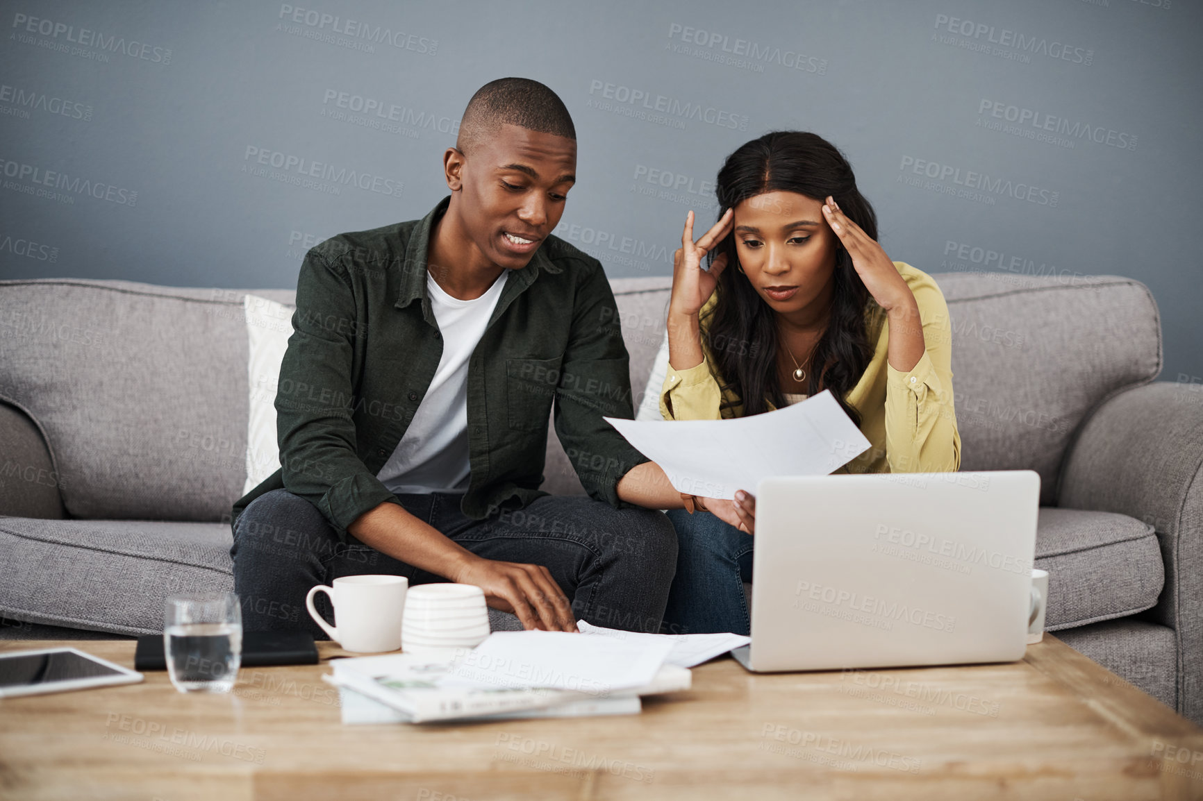 Buy stock photo Shot of a young couple going over bills together at home