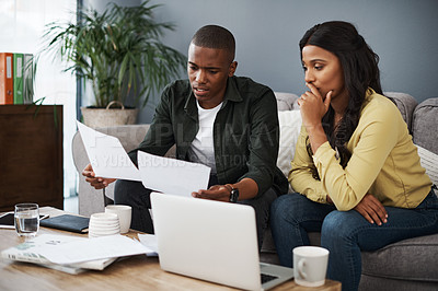 Buy stock photo Shot of a young couple going over bills together at home