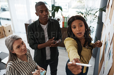 Buy stock photo Shot of a group of businesspeople brainstorming and sharing ideas on a backboard in a modern office