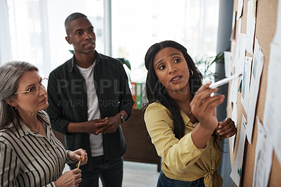 Buy stock photo Side shot of a group of businesspeople brainstorming and sharing ideas on a backboard in a modern office
