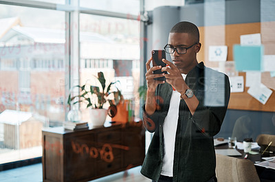 Buy stock photo Shot of a young businessman taking pictures of notes in a modern office