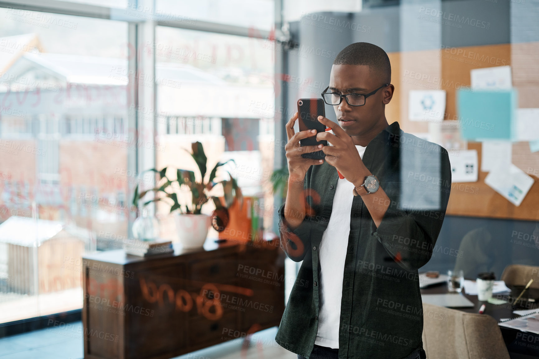 Buy stock photo Shot of a young businessman taking pictures of notes in a modern office