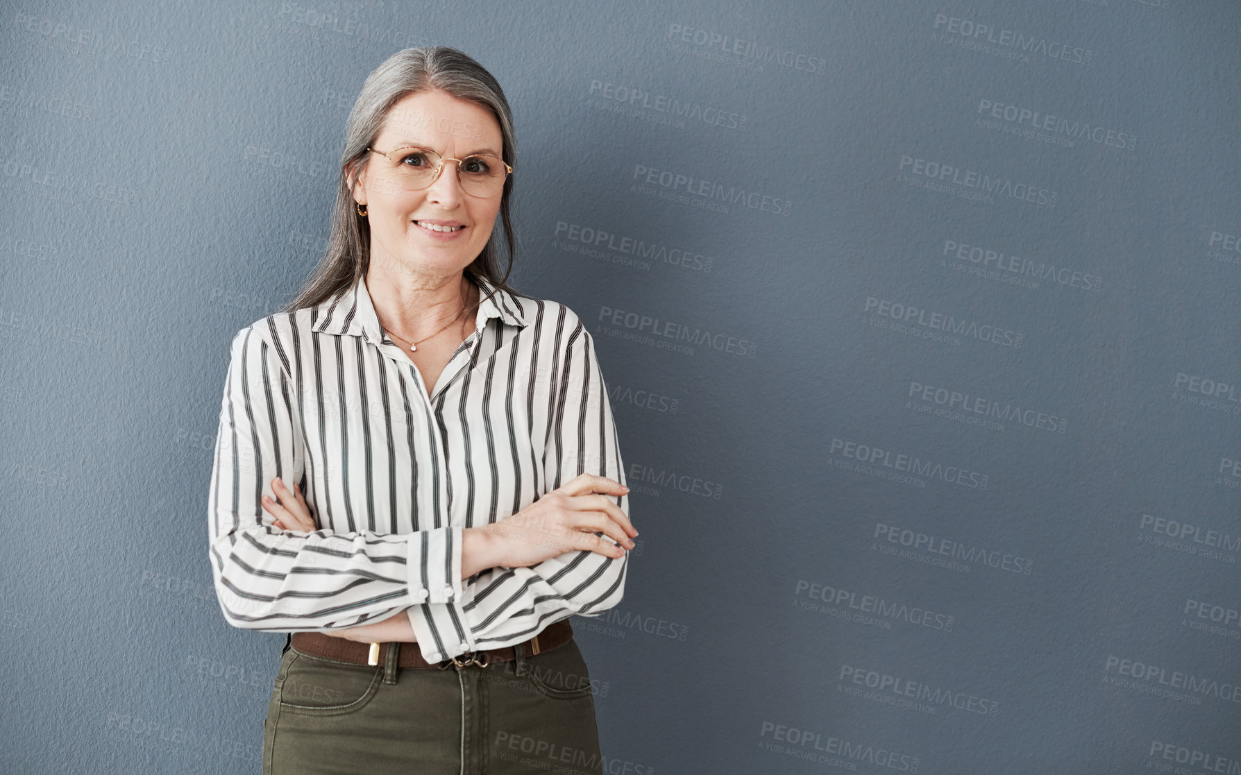 Buy stock photo Shot of a mature businesswoman posing with arms crossed against a black background