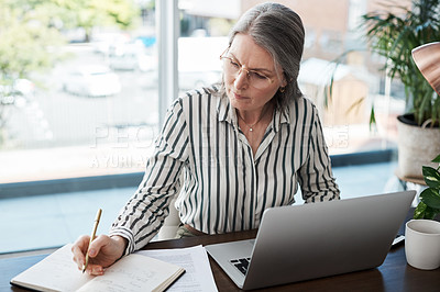 Buy stock photo Shot of a mature businesswoman making notes in a modern office