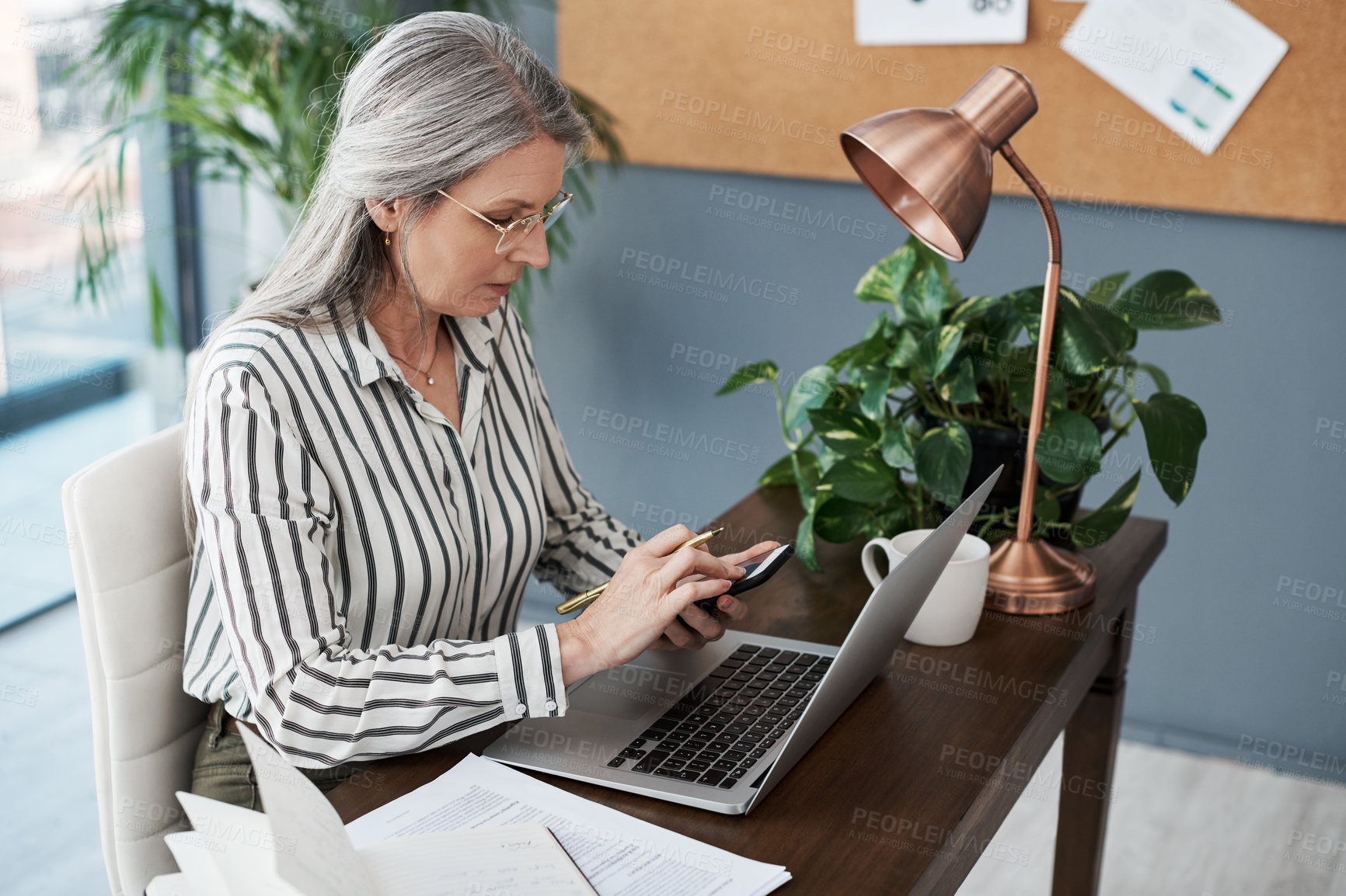 Buy stock photo Shot of a mature businesswoman using her laptop in a modern office