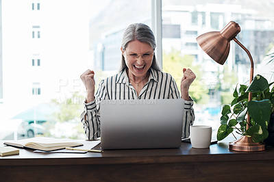 Buy stock photo Shot of a mature businesswoman in a moment of victory while using her laptop in a modern office