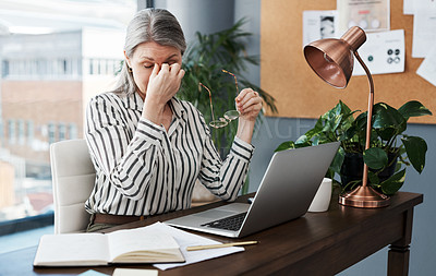 Buy stock photo Shot of a mature businesswoman looking stressed out while using her laptop in a modern office