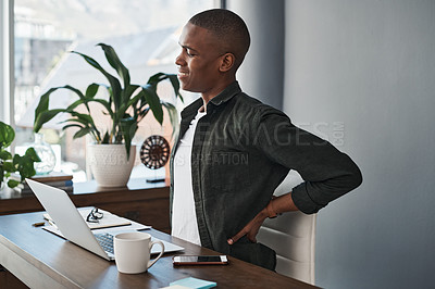 Buy stock photo Shot of a young businessman working from home experiencing back pain