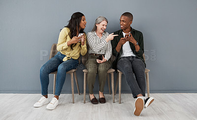 Buy stock photo Shot of a group of people laughing at a funny visual from a smartphone against a grey wall