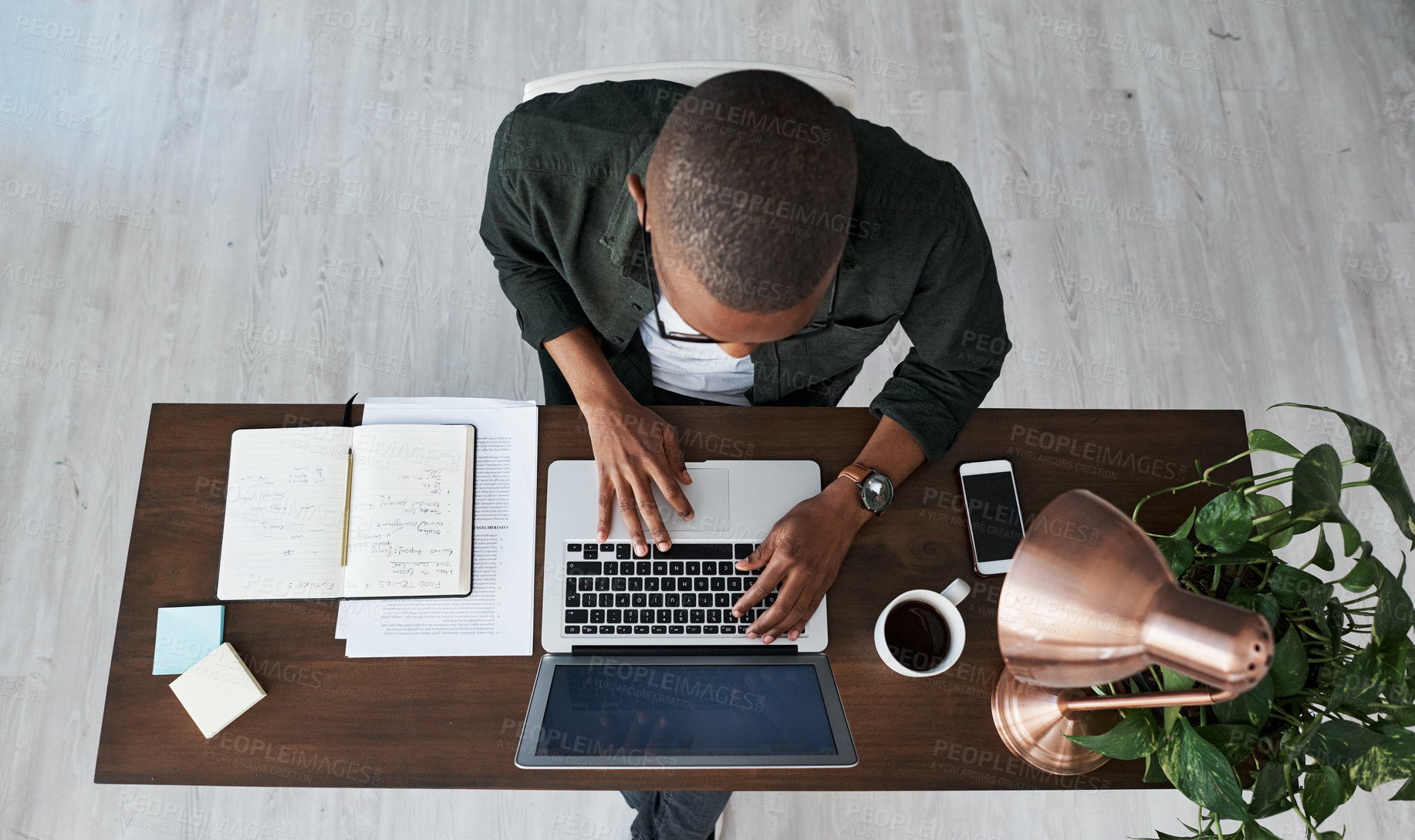 Buy stock photo Shot of a young businessman typing on his laptop while working from home