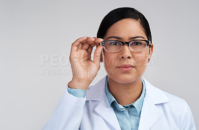 Buy stock photo Cropped portrait of an attractive young female scientist wearing glasses in studio against a grey background