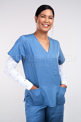 Buy stock photo Portrait of a young doctor standing with her hands tucked into her scrubs against a white background