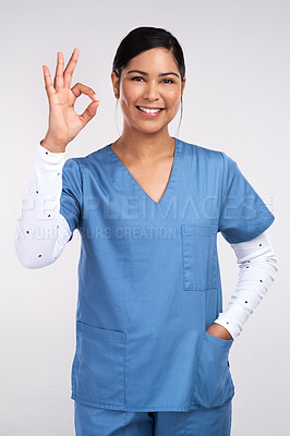 Buy stock photo Portrait of a young doctor showing the ok sign against a white background