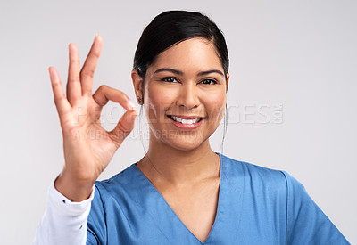 Buy stock photo Portrait of a young doctor showing the ok sign against a white background