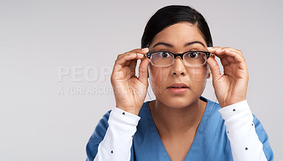 Buy stock photo Portrait of a young doctor adjusting her glasses and wearing scrubs against a white background