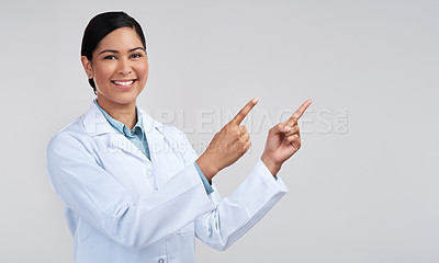 Buy stock photo Cropped portrait of an attractive young female scientist pointing towards copyspace in studio against a grey background