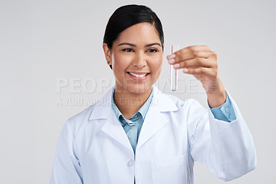 Buy stock photo Cropped shot of an attractive young female scientist examining a vial filled with liquid in studio against a grey background