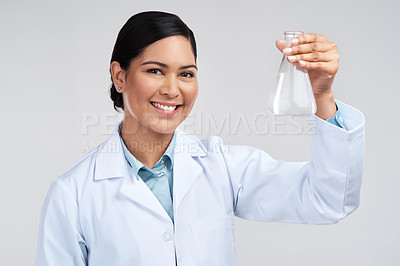 Buy stock photo Cropped portrait of an attractive young female scientist holding a beaker filled with liquid in studio against a grey background