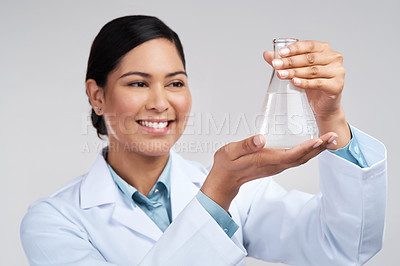 Buy stock photo Cropped shot of an attractive young female scientist examining a beaker filled with liquid in studio against a grey background