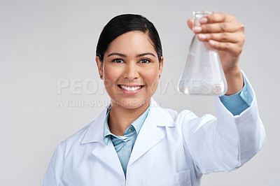 Buy stock photo Cropped portrait of an attractive young female scientist holding a beaker filled with liquid in studio against a grey background