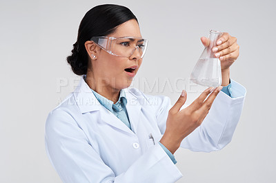 Buy stock photo Cropped shot of an attractive young female scientist looking shocked while examining a beaker filled with liquid in studio against a grey background