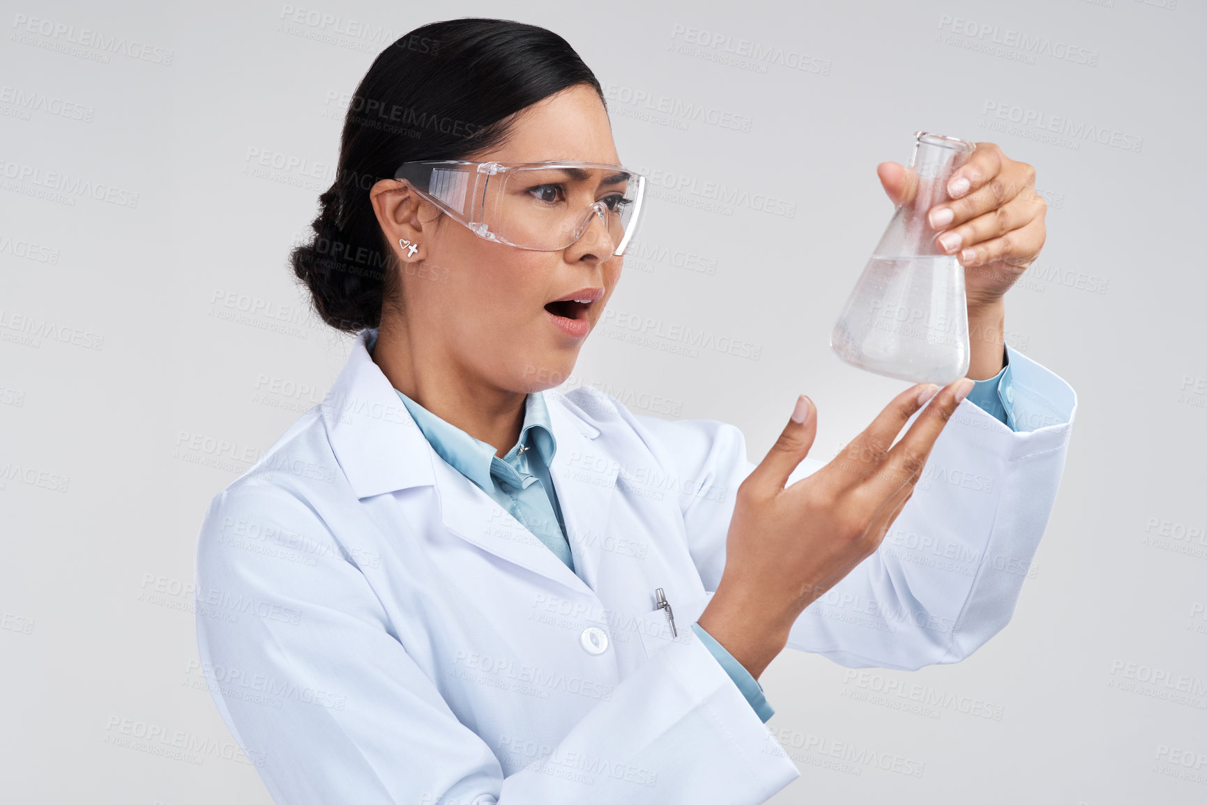 Buy stock photo Cropped shot of an attractive young female scientist looking shocked while examining a beaker filled with liquid in studio against a grey background