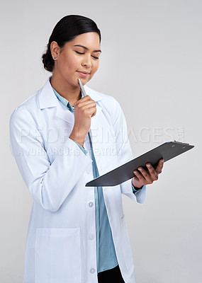 Buy stock photo Cropped shot of an attractive young female scientist looking thoughtful while working on a clipboard in studio against a grey background