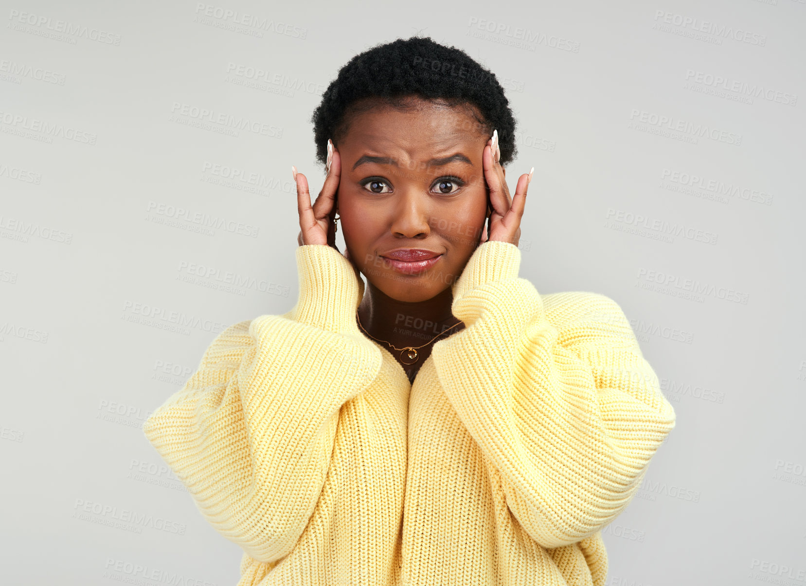 Buy stock photo Shot of a young woman looking worried while posing against a grey background