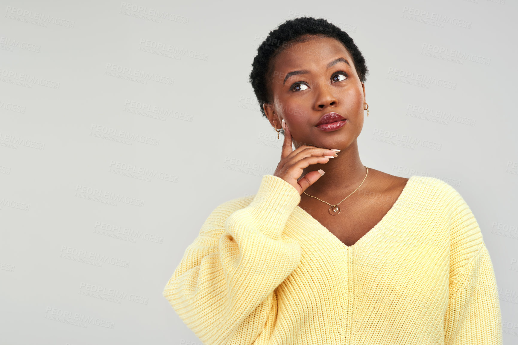 Buy stock photo Shot of a young woman looking thoughtful while posing against a grey background