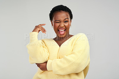 Buy stock photo Shot of a young woman winking while posing against a grey background