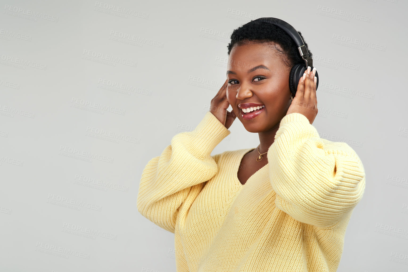 Buy stock photo Shot of a young woman wearing headphones while posing against a grey background