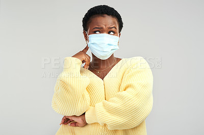 Buy stock photo Shot of a young woman wearing a surgical mask while standing against a grey background