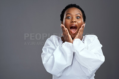 Buy stock photo Shot of a young woman looking surprised while posing against a grey background